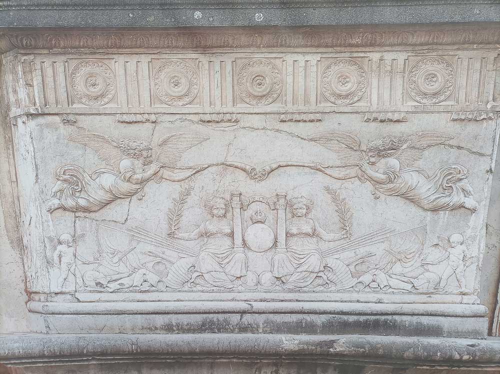 Basamento de las columnas de la portada principal del Palacio de Carlos V donde aparece escenas de de acumulación de trofeos